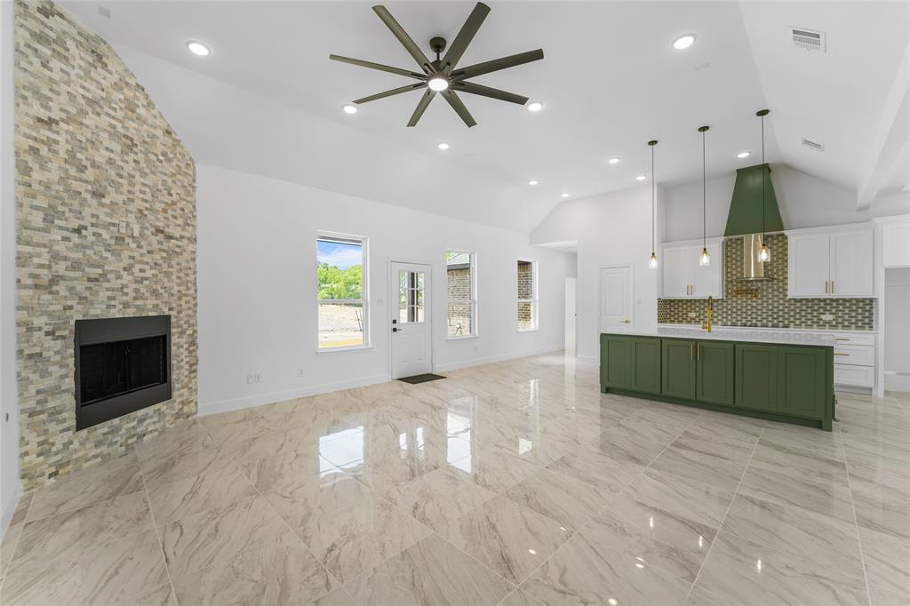 a large kitchen with kitchen island a sink stainless steel appliances and a fireplace