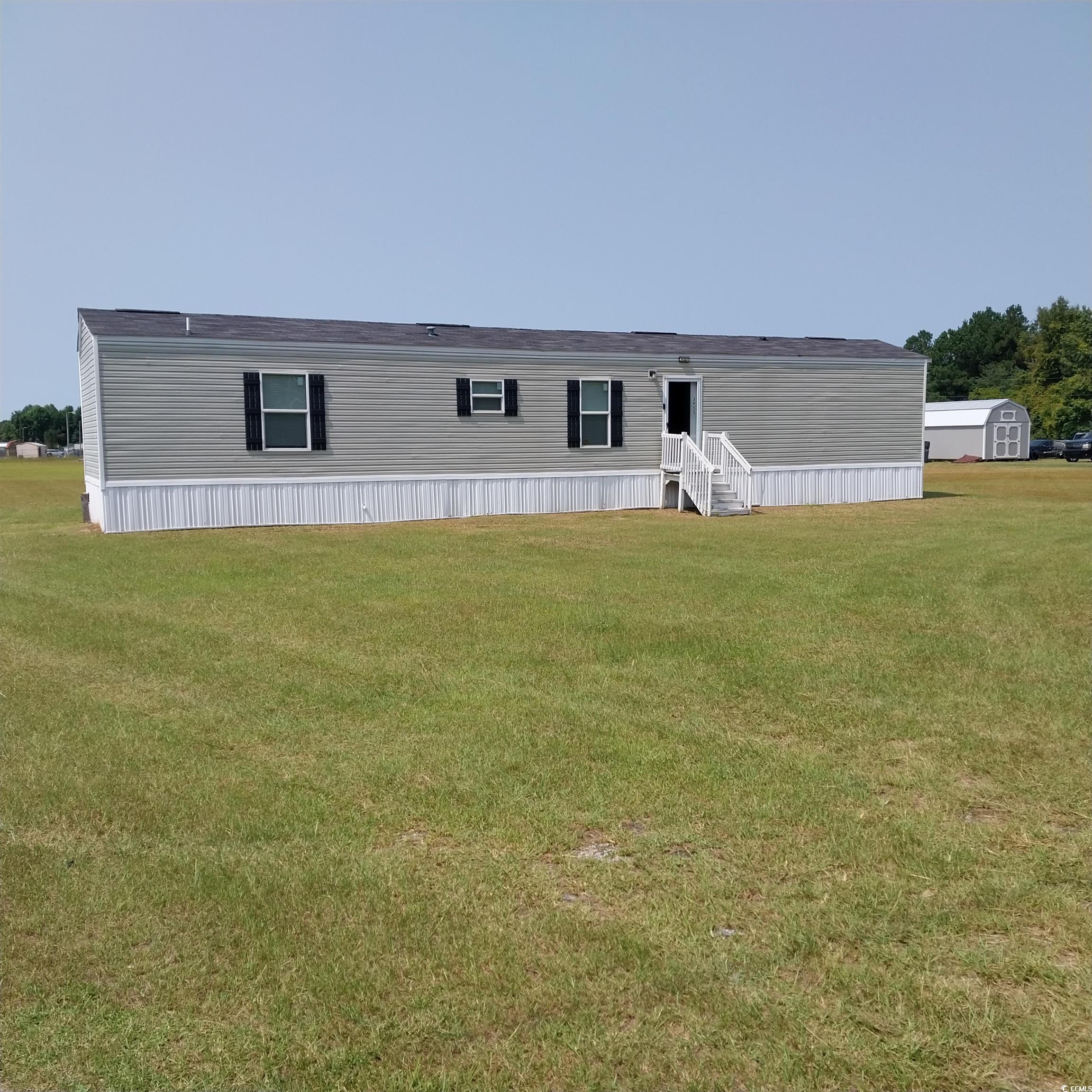 Rear view of property featuring a lawn and a stora