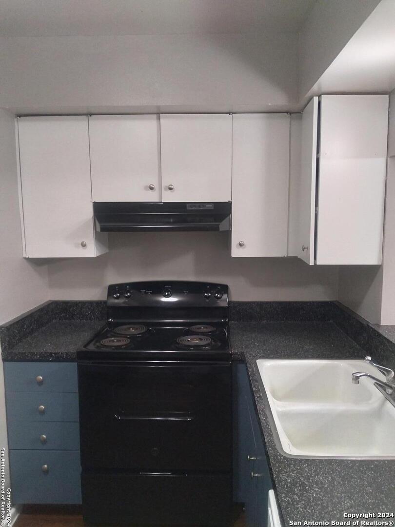 a kitchen with granite countertop white cabinets and black appliances