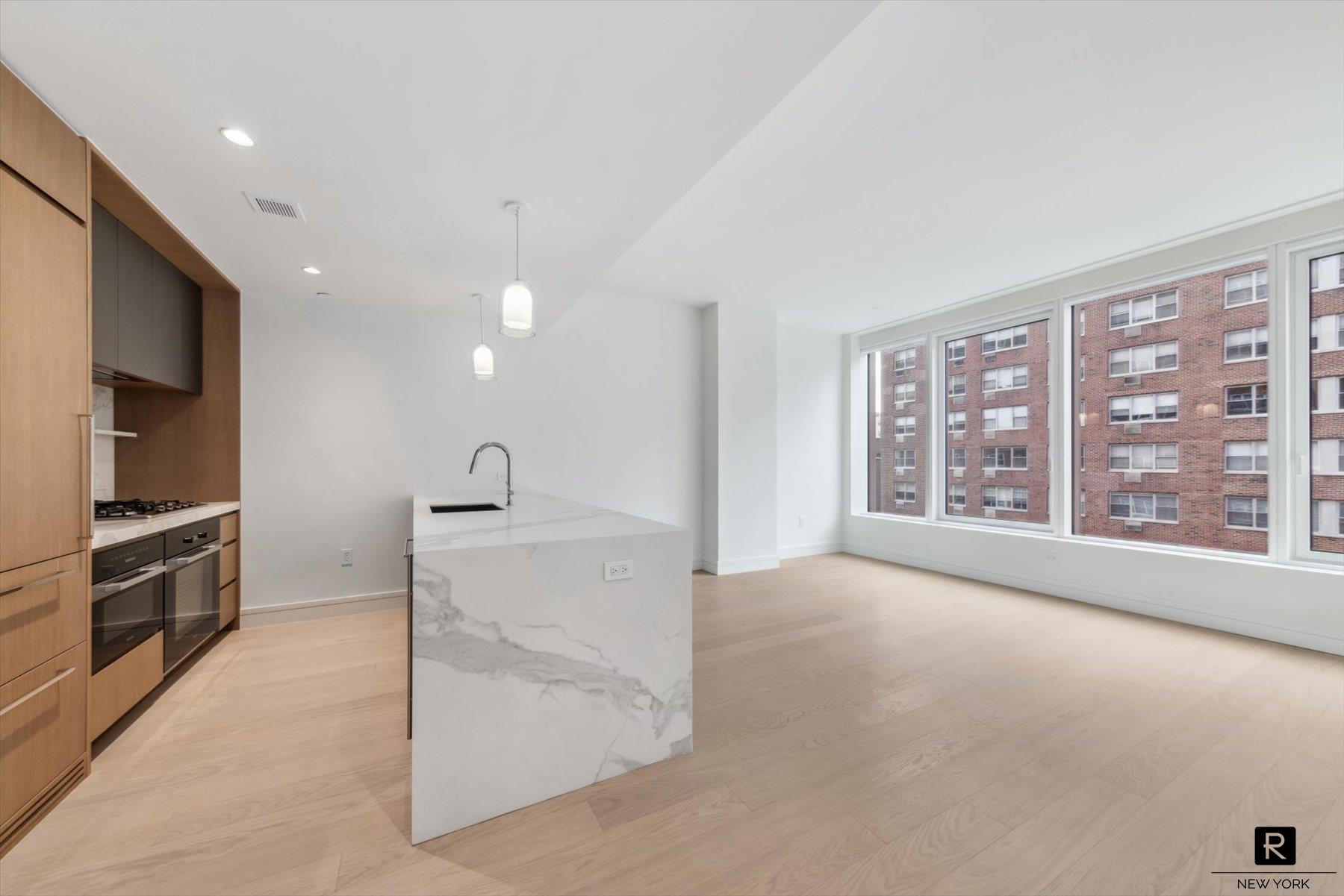 a view of an empty room with a window and a kitchen