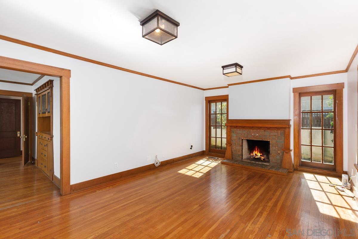 a view of an empty room with wooden floor fireplace and a window