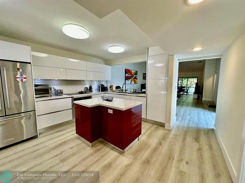 a kitchen with stainless steel appliances kitchen island granite countertop a refrigerator and a sink