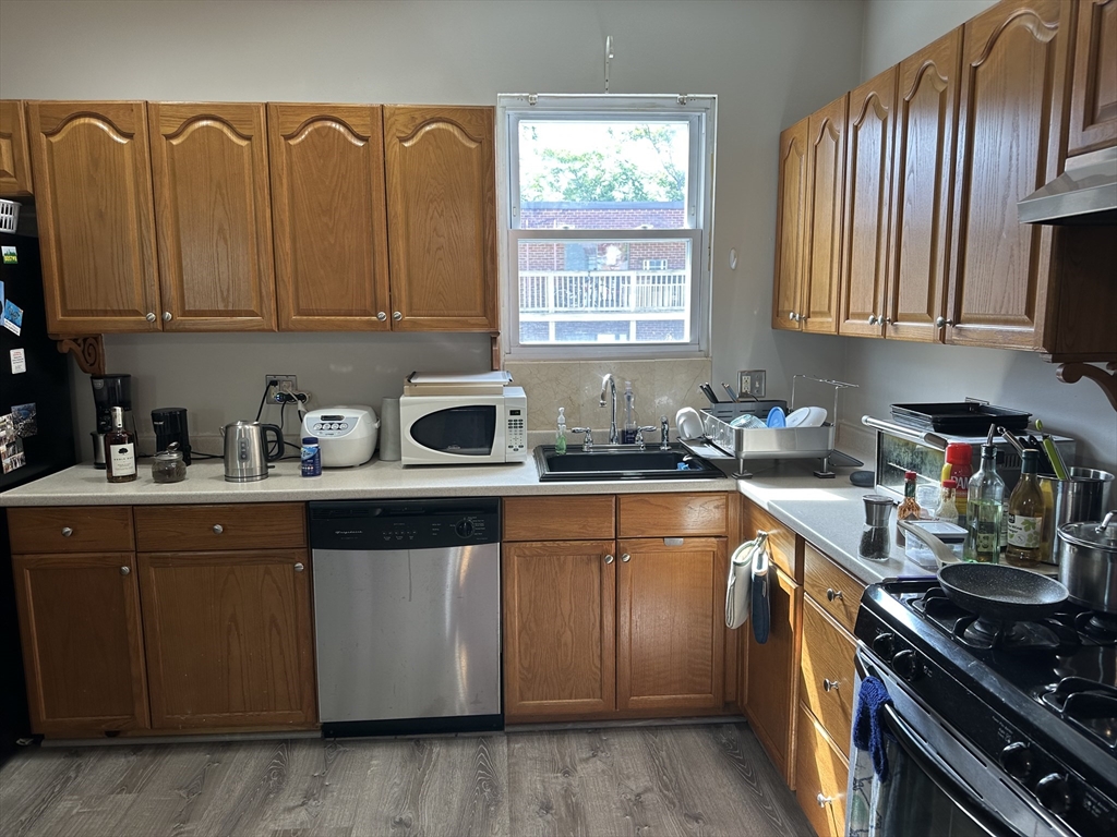 a kitchen with granite countertop wood cabinets stainless steel appliances a sink and a window