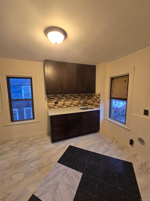 Kitchen featuring decorative backsplash, dark brown cabinetry, and sink