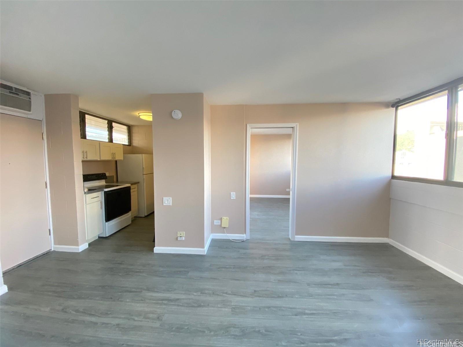 an empty room with kitchen and windows