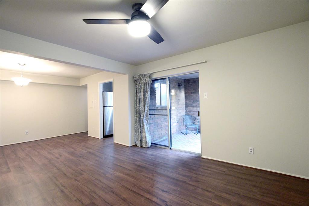 a view of an empty room with wooden floor and a ceiling fan