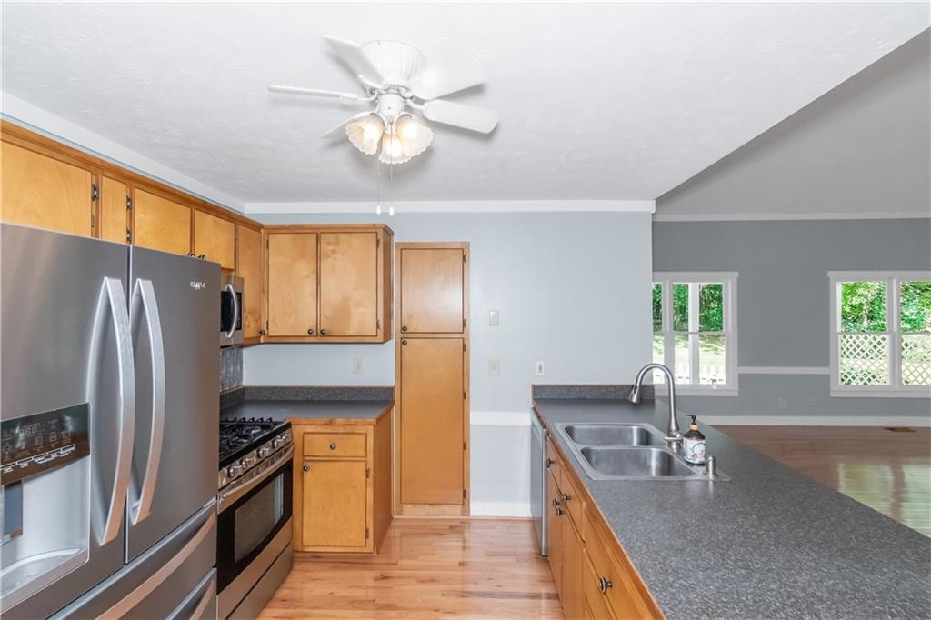 a kitchen with stainless steel appliances granite countertop a sink a stove and refrigerator