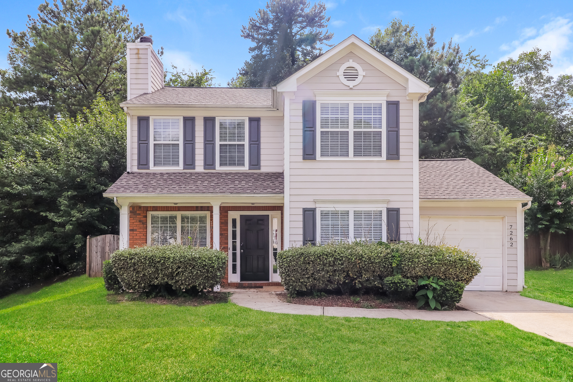 a front view of a house with a yard and trees