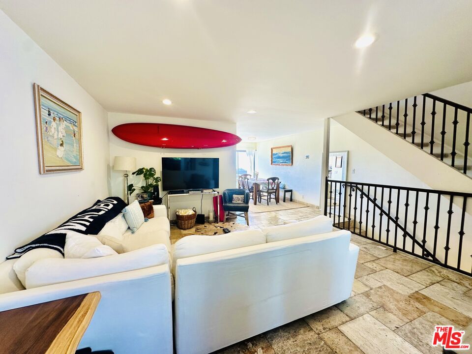 a living room with furniture and a dining table with wooden floor