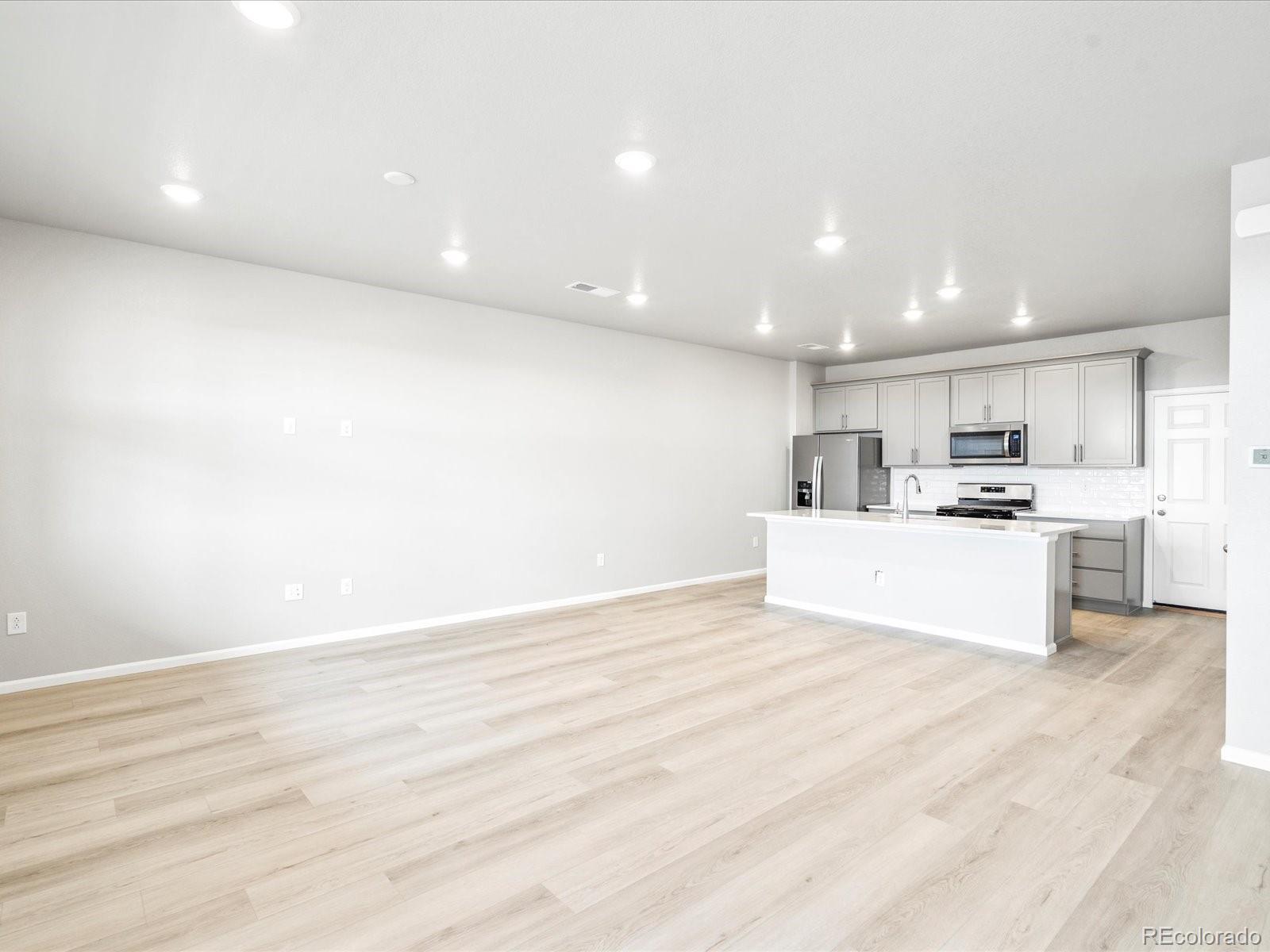 a view of kitchen with kitchen island a sink wooden floor and view living room