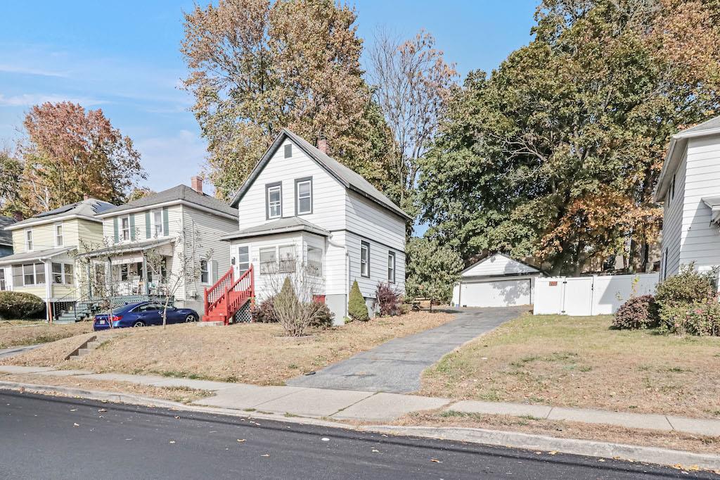 View of front facade featuring an outbuilding, a garage, and a front yard