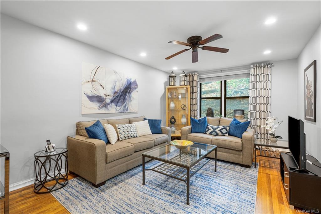 a living room with furniture a ceiling fan and a flat screen tv