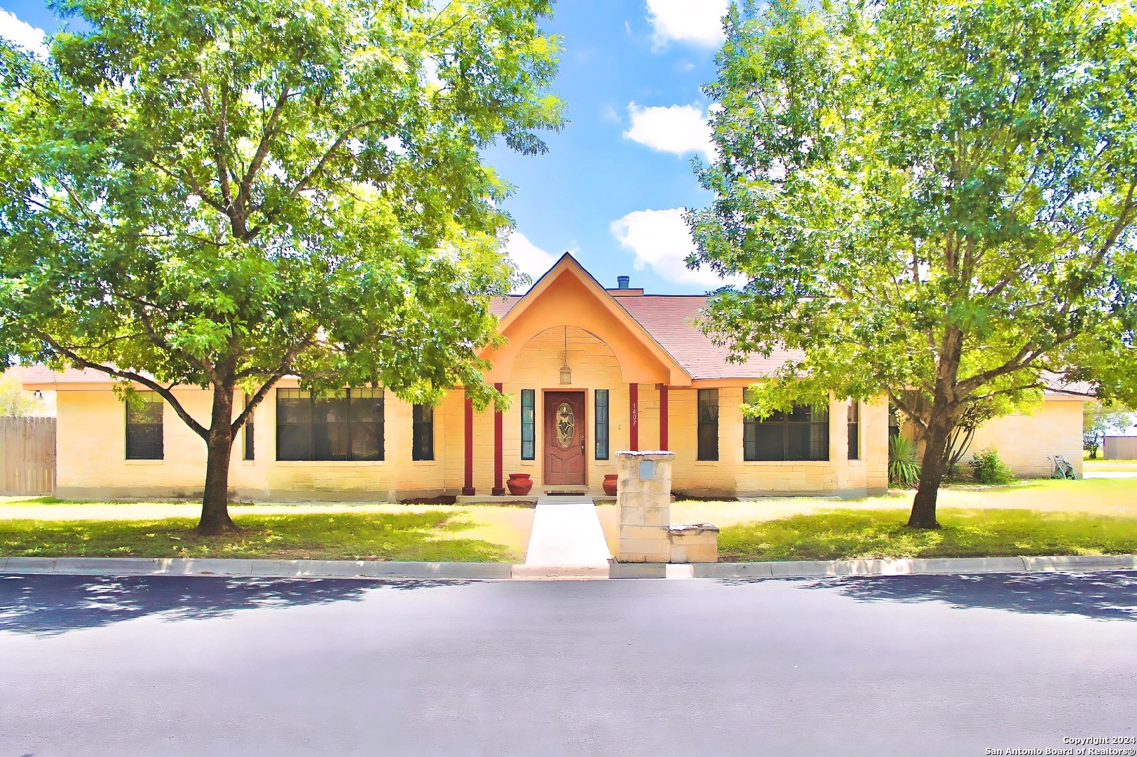 a front view of a house with a garden and tree