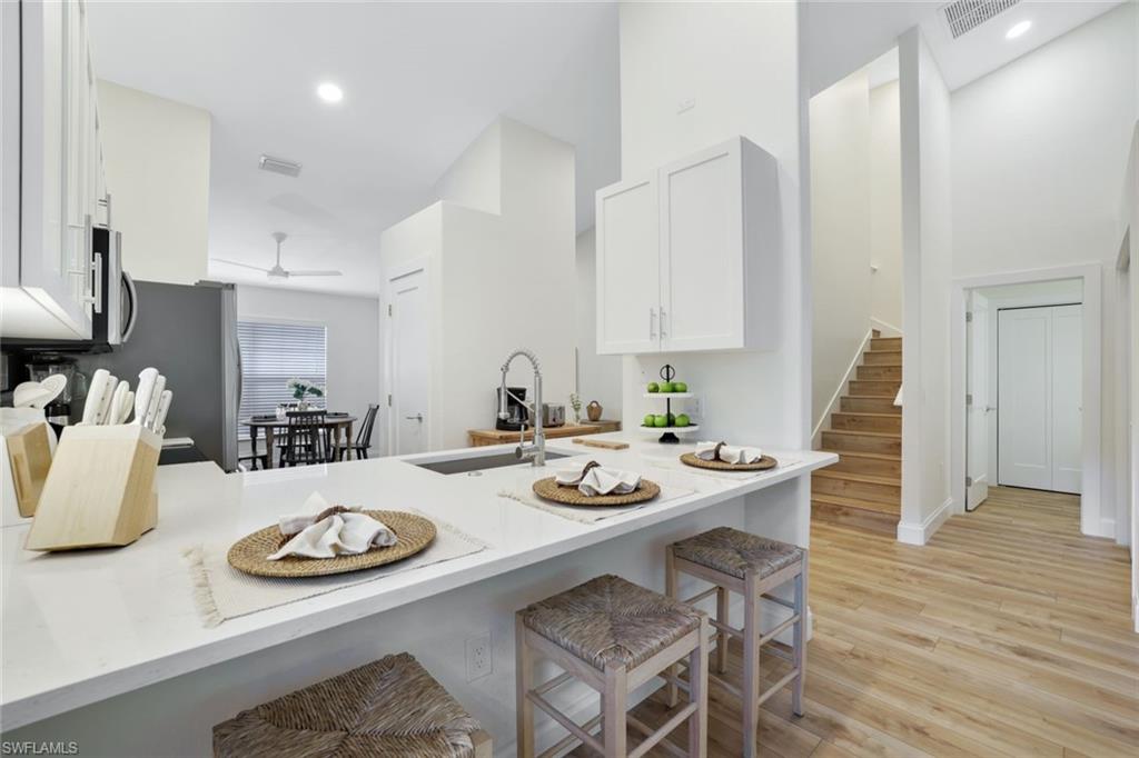 Kitchen peninsula / breakfast bar and the light wood-style flooring featured throughout the entire home; view of stairs leading to the second floor bedroom and en suite bathroom