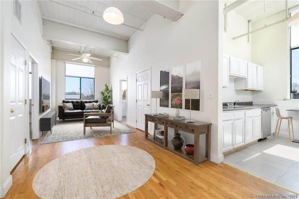 a living room with stainless steel appliances furniture a rug kitchen view and a faucet