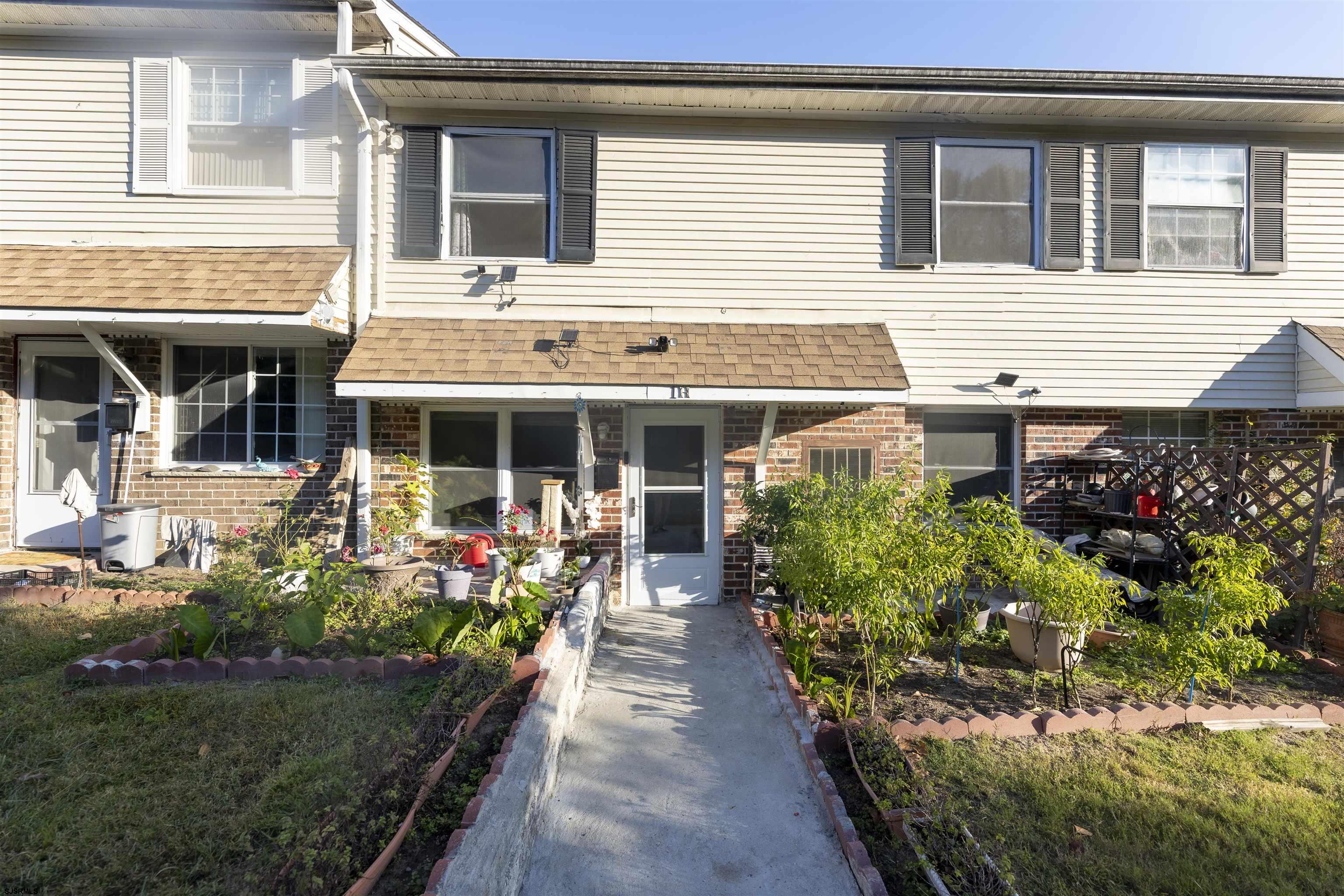 a front view of a house with a yard and potted plants