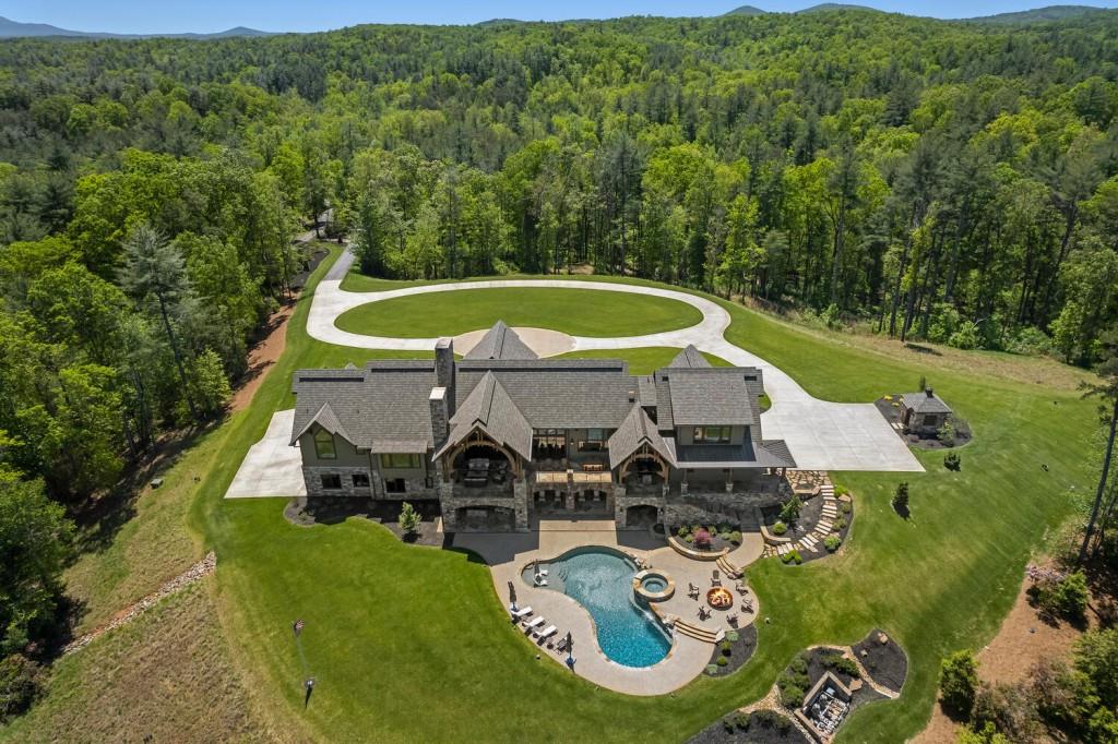 an aerial view of a swimming pool with lawn chairs and large trees