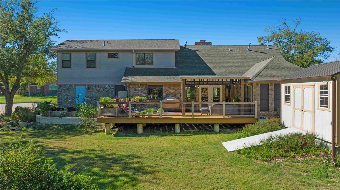 Back of property with a lawn and a wooden deck