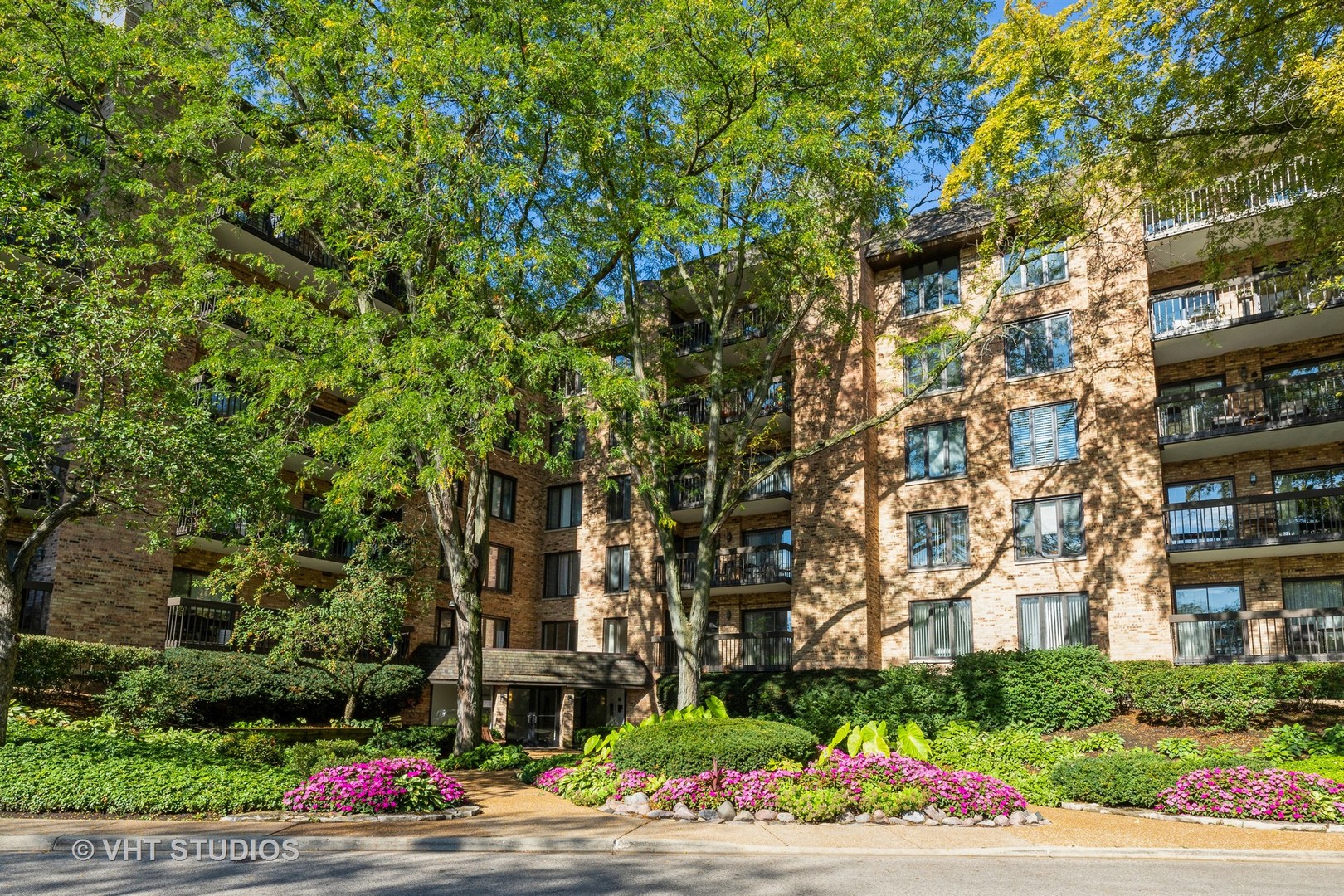 a front view of a multi story residential apartment building with yard and green space