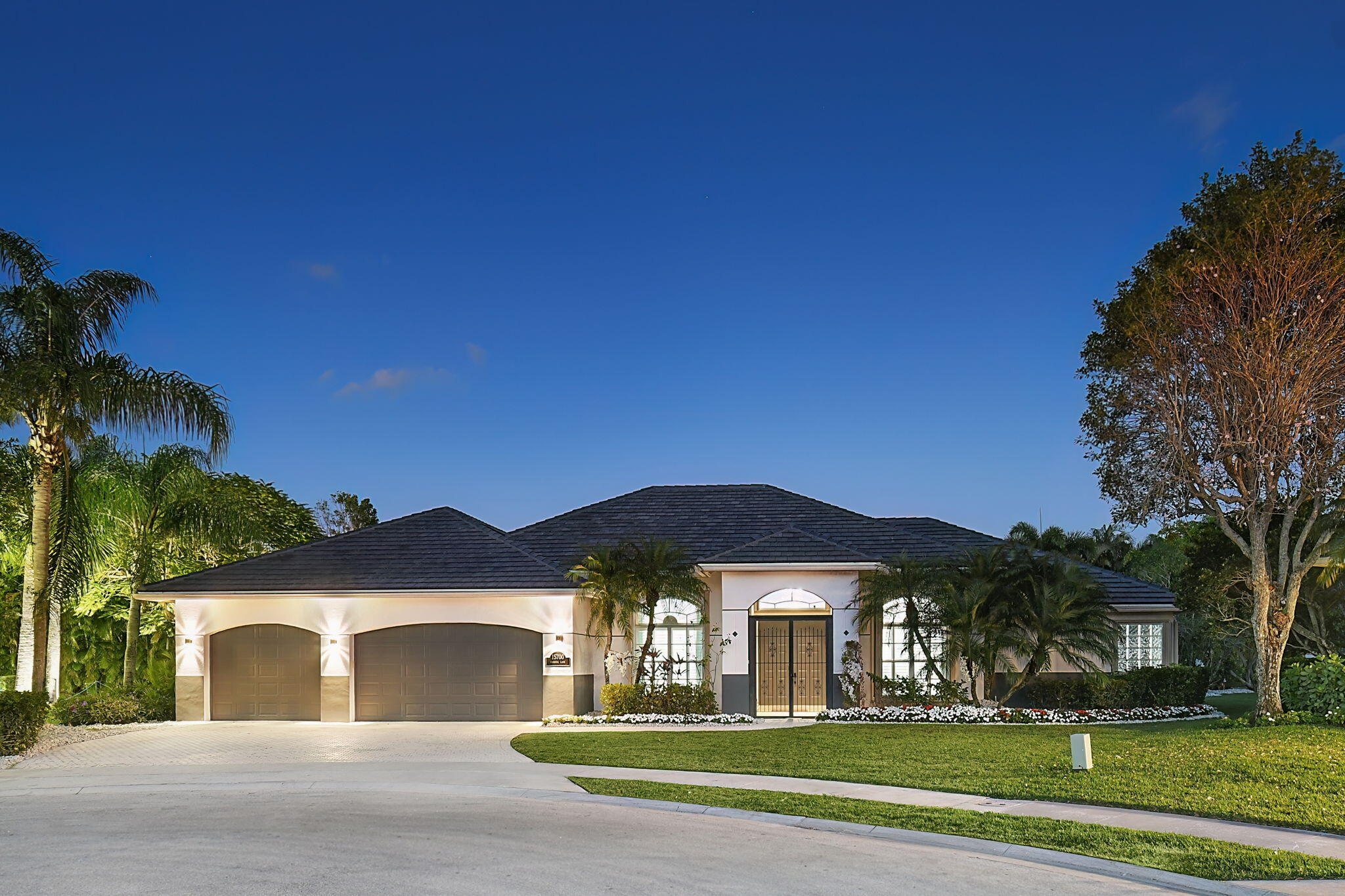 a view of a big house with a yard and palm trees