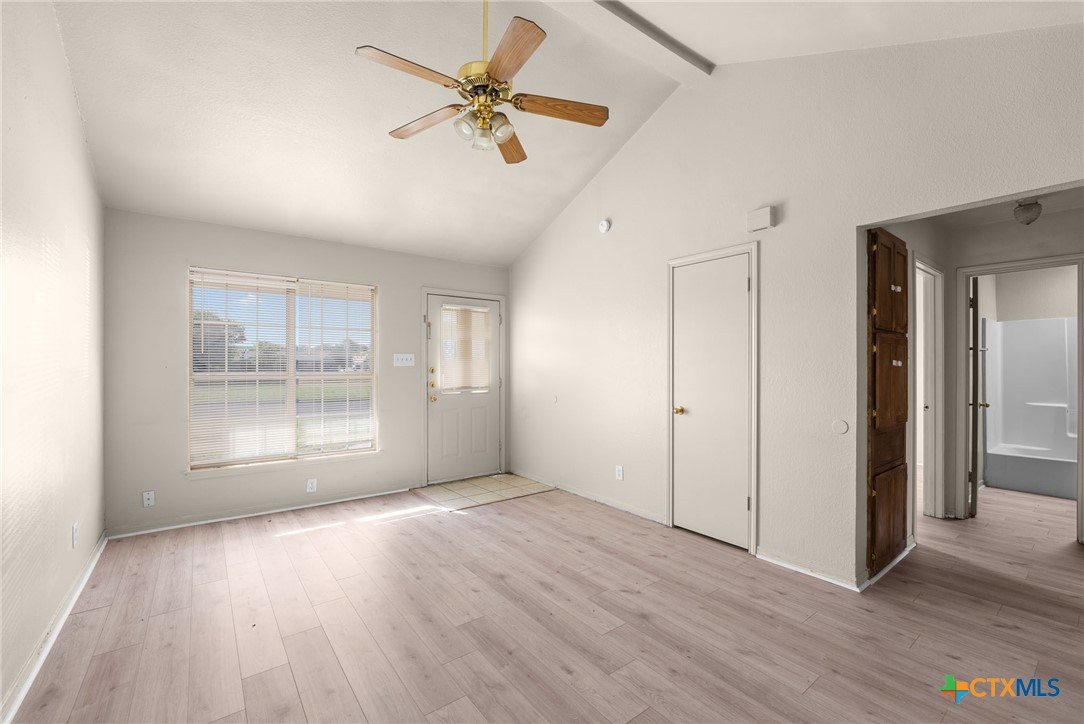 a view of an empty room with a window and wooden floor