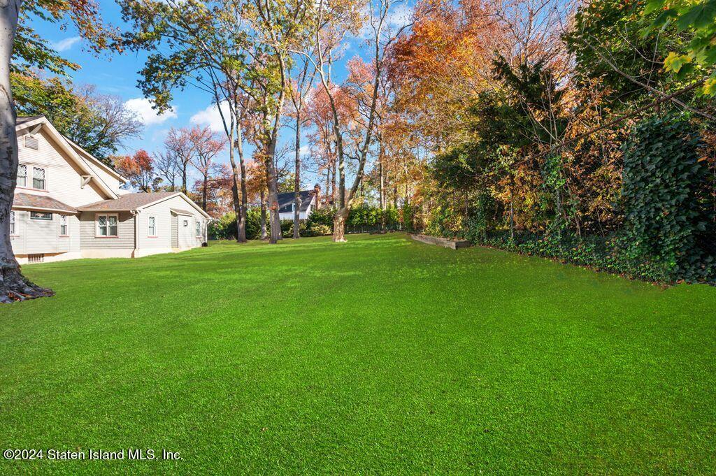 a view of a white house with a big yard and large trees