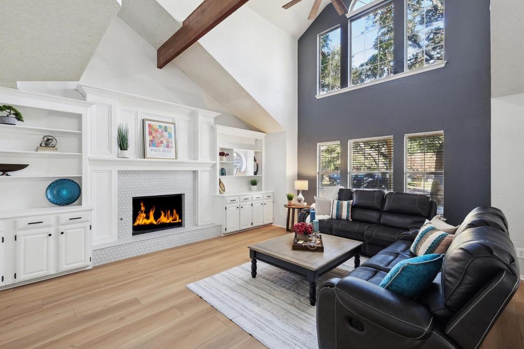 Living room with beamed ceiling, light hardwood / wood-style flooring, ceiling fan, and a healthy amount of sunlight