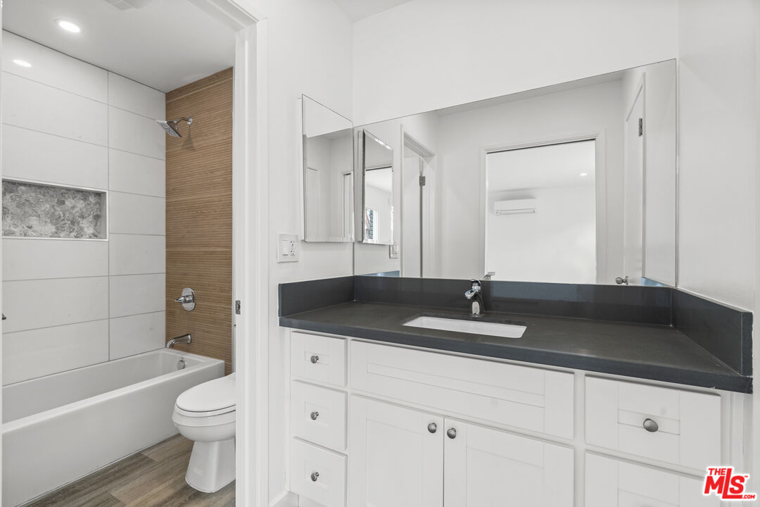 a bathroom with a granite countertop sink a toilet and bathtub