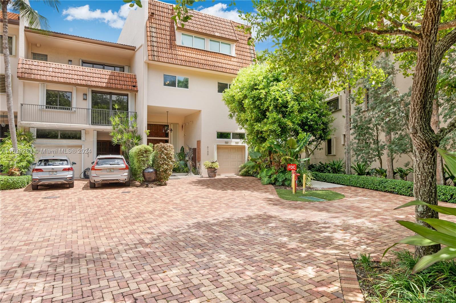 a view of a house with potted plants and a large tree