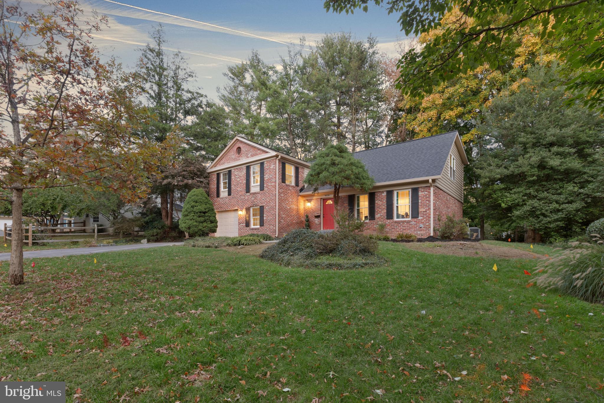 a view of a yard in front of a house with plants and large trees