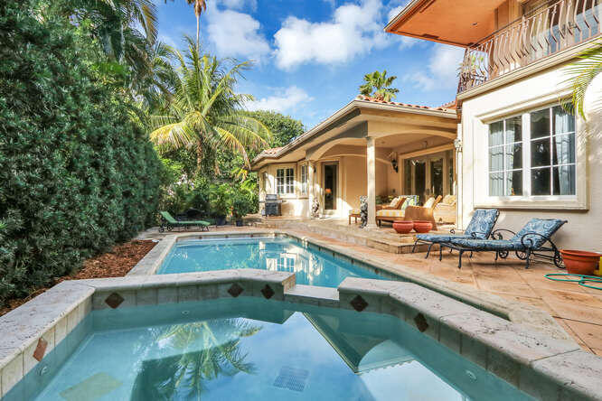 a view of a house with pool lawn chairs and a barbeque