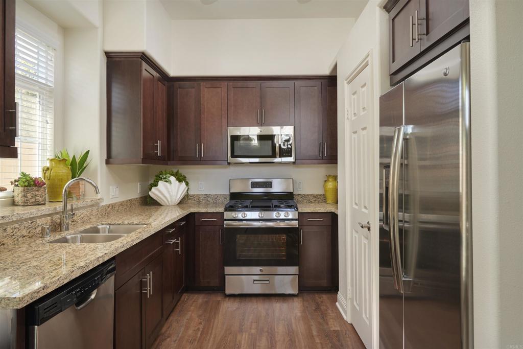 a kitchen with granite countertop a refrigerator stove and sink