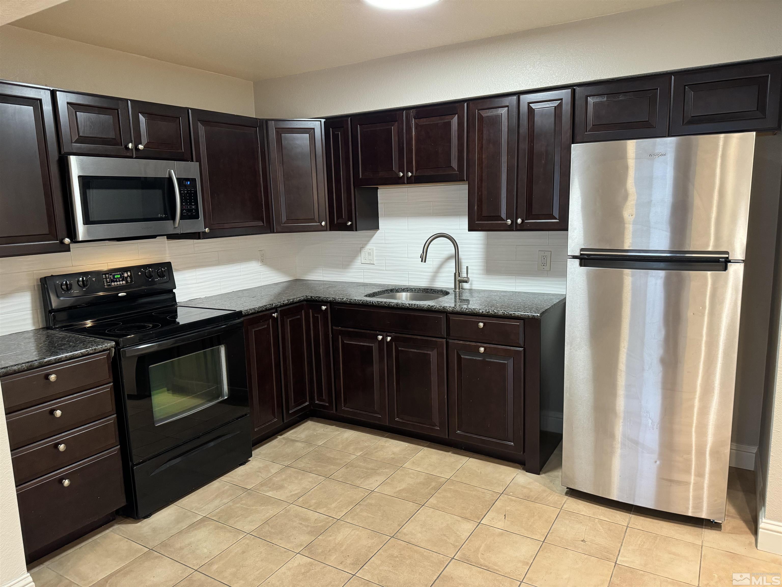 a kitchen with granite countertop a refrigerator and a stove top oven