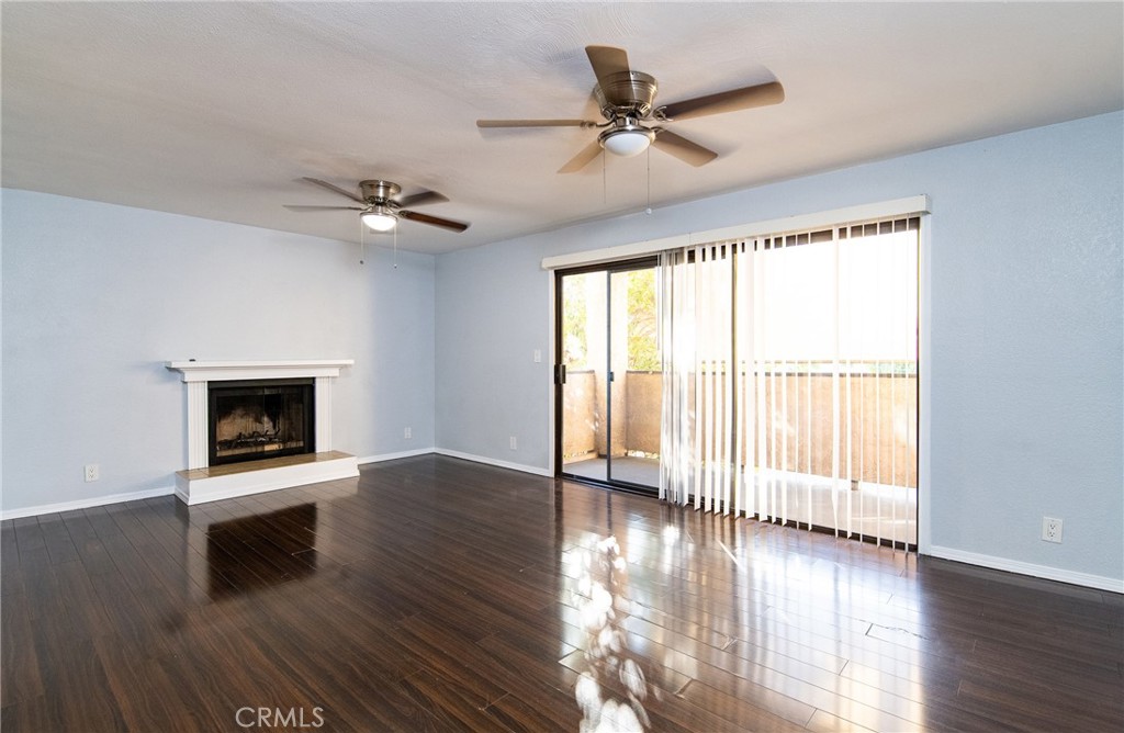 a view of an empty room with wooden floor fireplace and a window