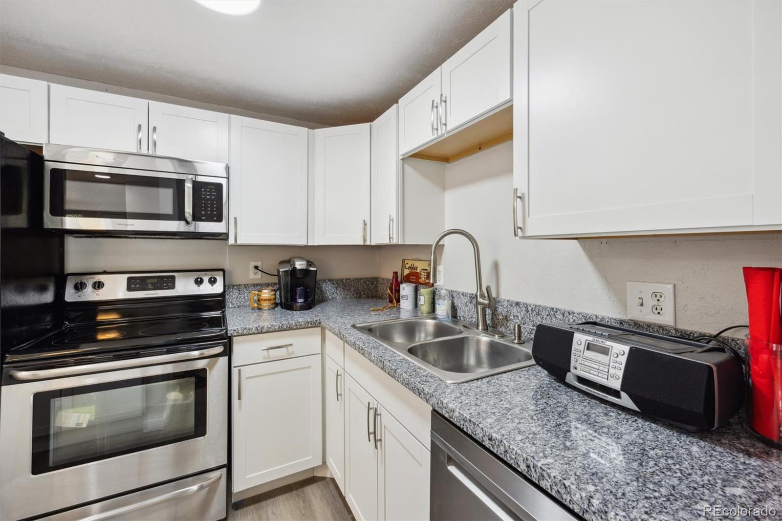 a kitchen with granite countertop white cabinets and stainless steel appliances