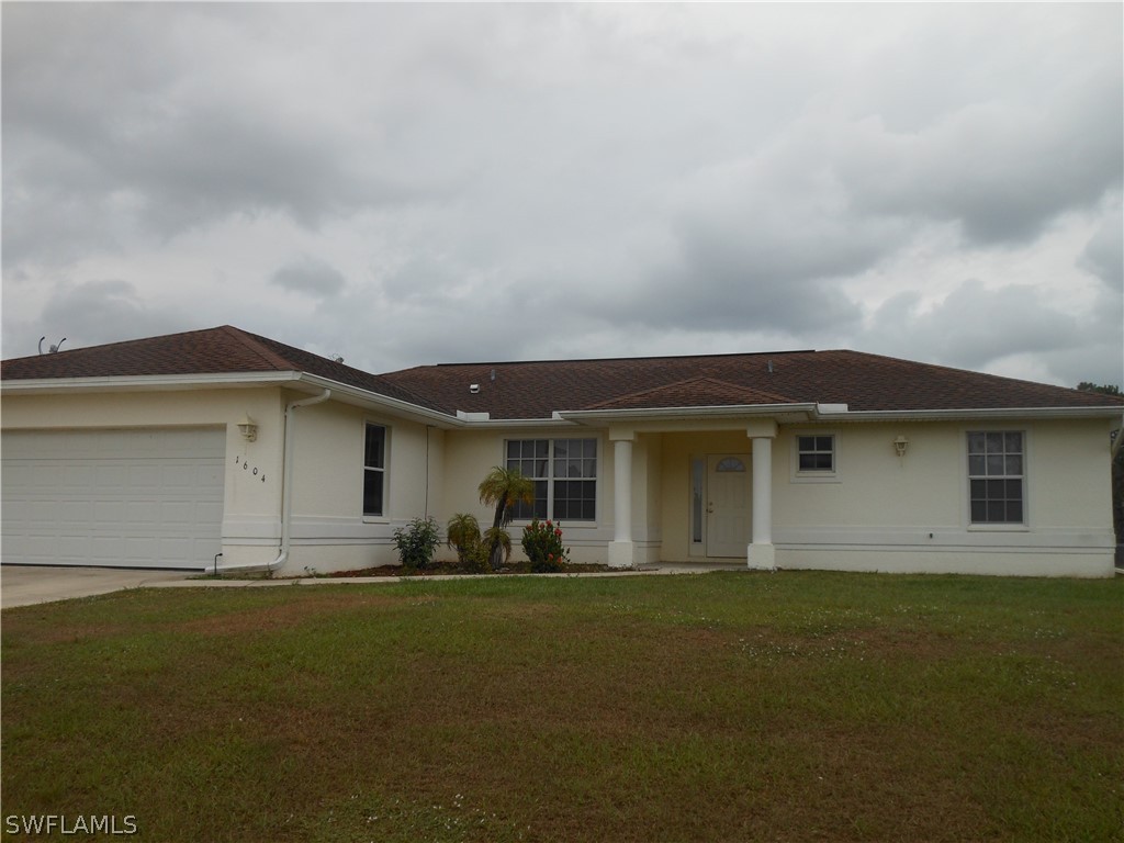 a front view of house with yard and trees in the background