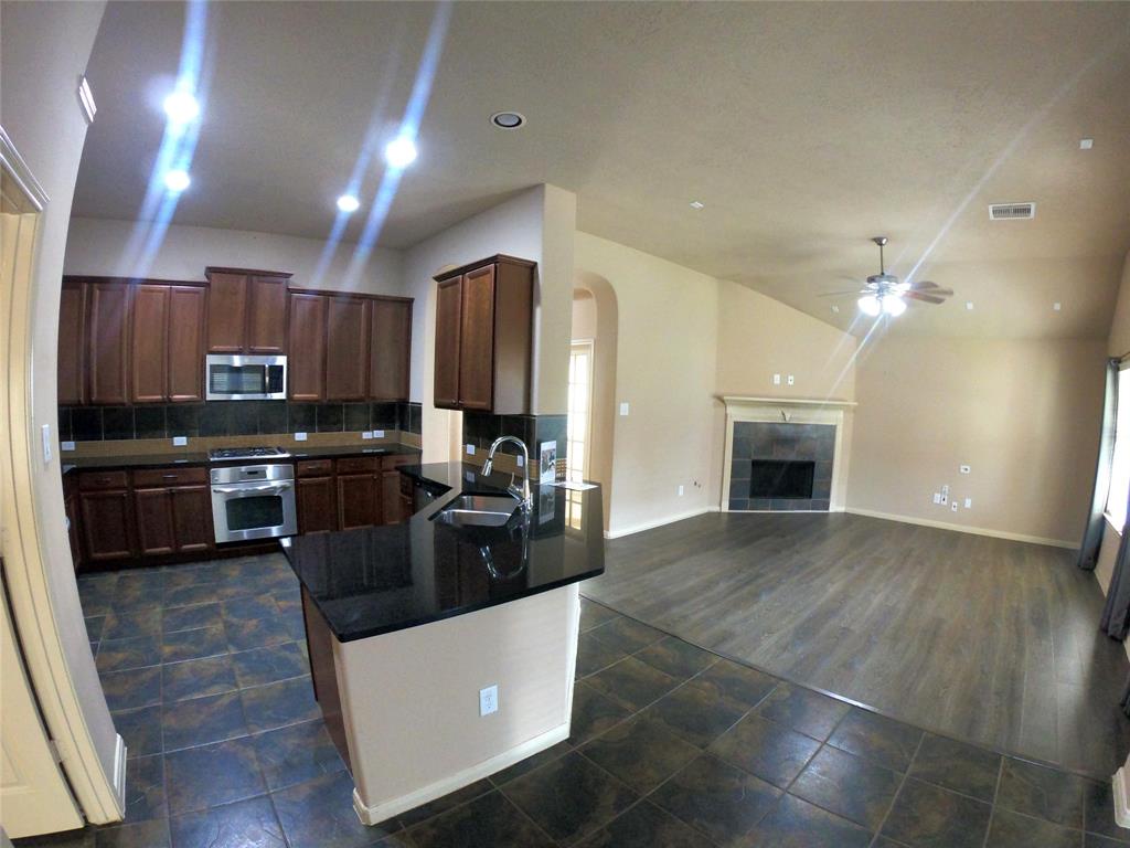 a kitchen with kitchen island granite countertop a stove top oven a sink a counter space and cabinets