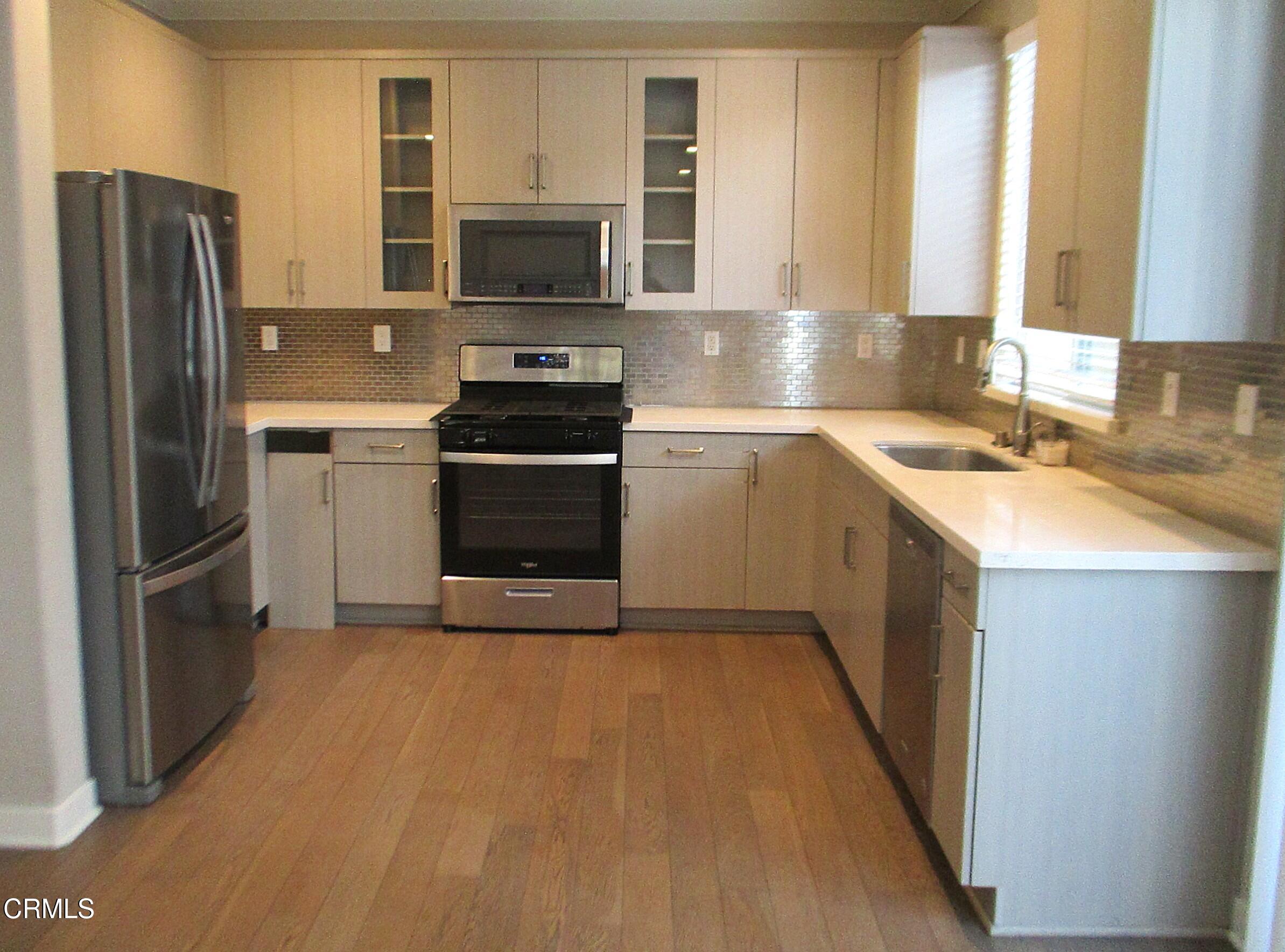 a kitchen with a sink a microwave a refrigerator and cabinets