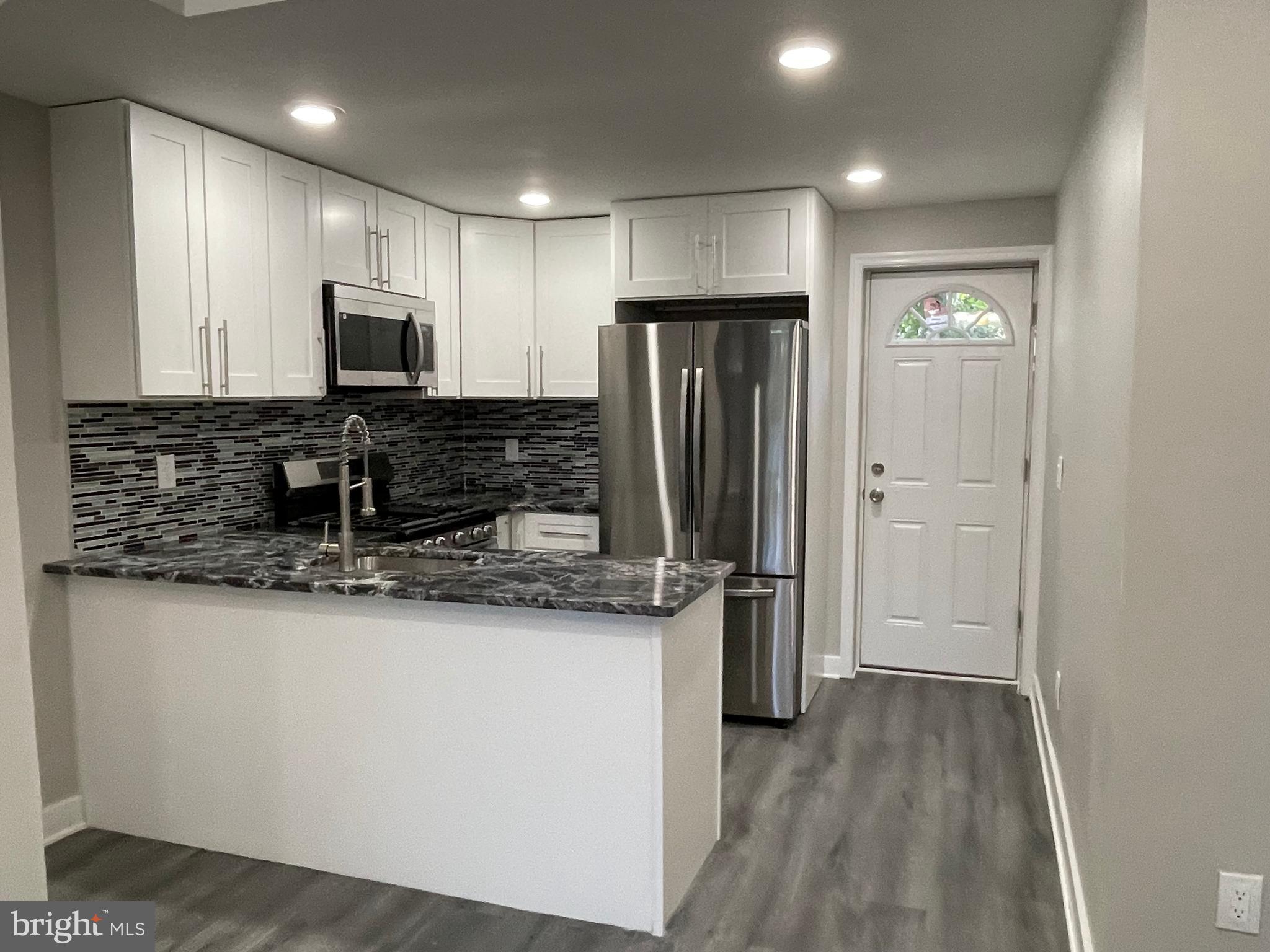 a kitchen with stainless steel appliances granite countertop a refrigerator and a stove top oven