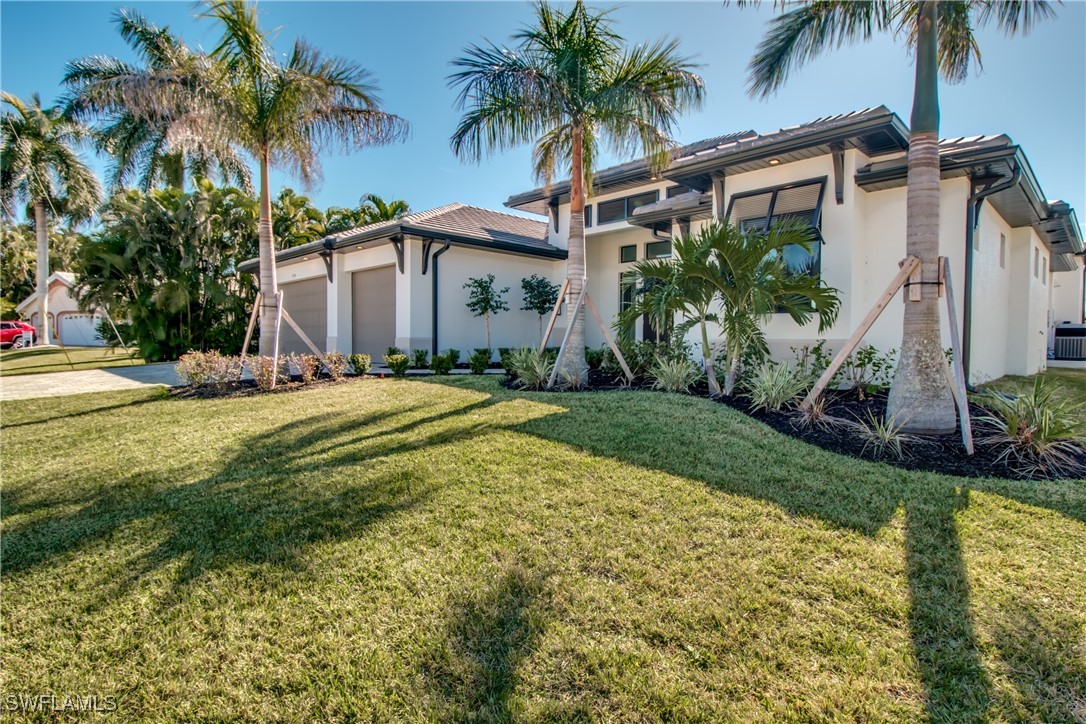 a view of a house with a yard and palm trees