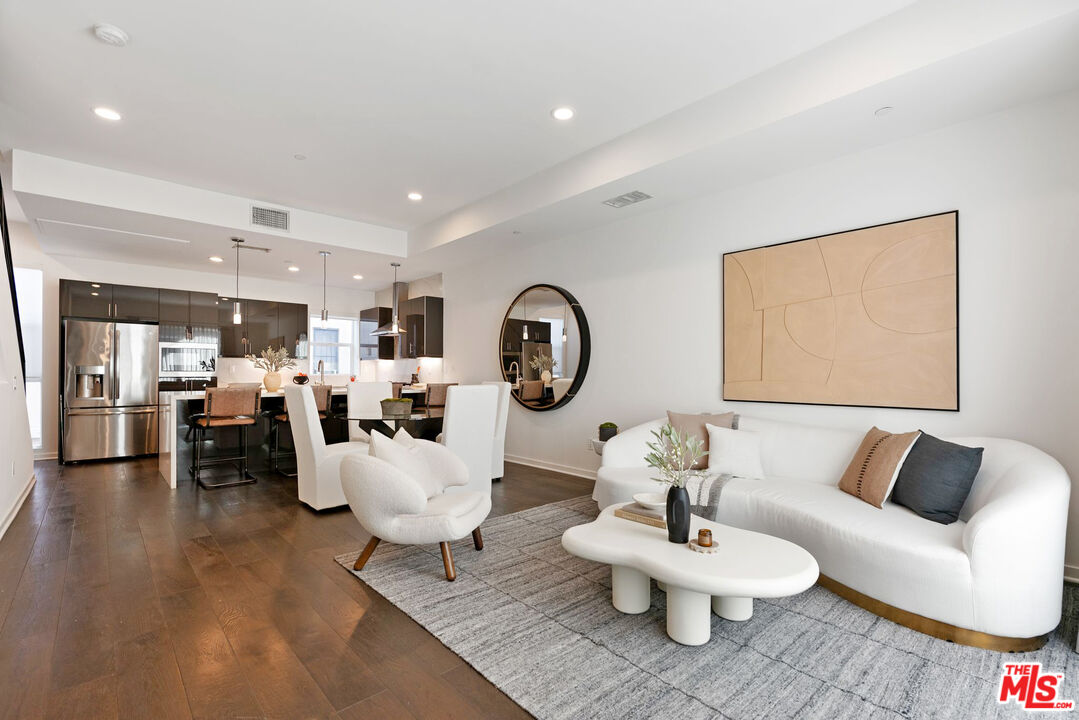 a living room with furniture a table and kitchen view