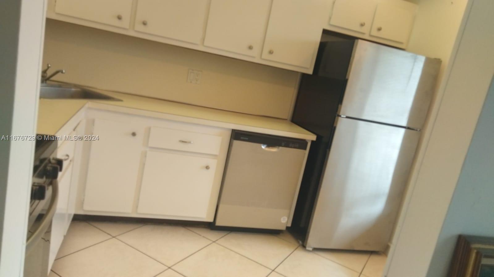 a view of a refrigerator in kitchen and white cabinets