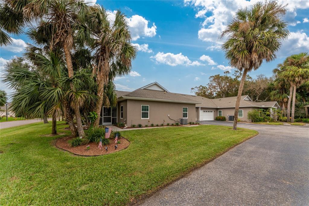 a view of a white house with a big yard and potted plants and palm trees