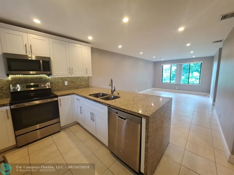 a large kitchen with stainless steel appliances granite countertop a stove a sink and a microwave