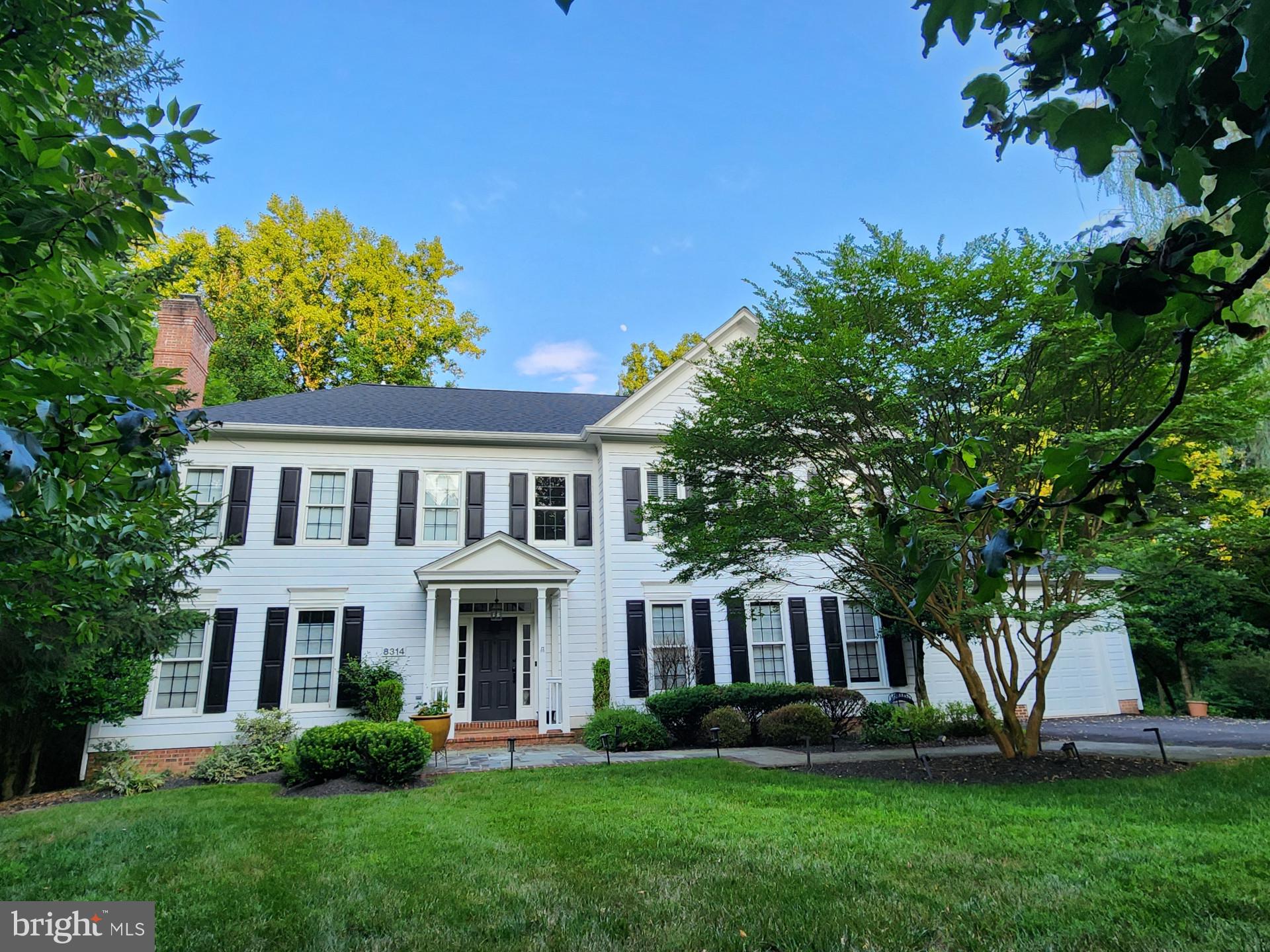 a front view of a house with a garden and trees