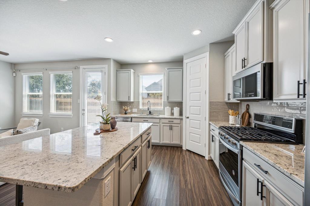 Upgraded hardware, an over-sized island, gas range, and walk-in pantry in this kitchen.