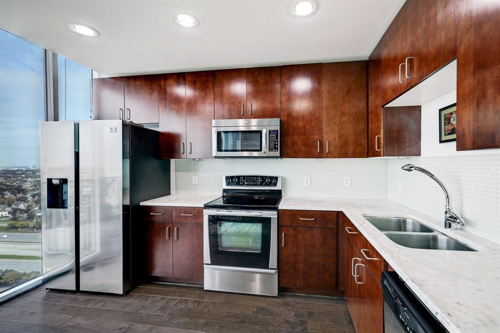 a kitchen with stainless steel appliances granite countertop a sink a stove a refrigerator and a microwave