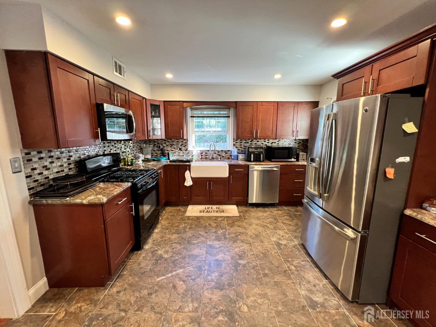 a kitchen with stainless steel appliances granite countertop a refrigerator stove and a sink