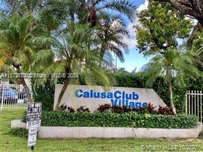 a sign that is sitting on a lush green field near a tree