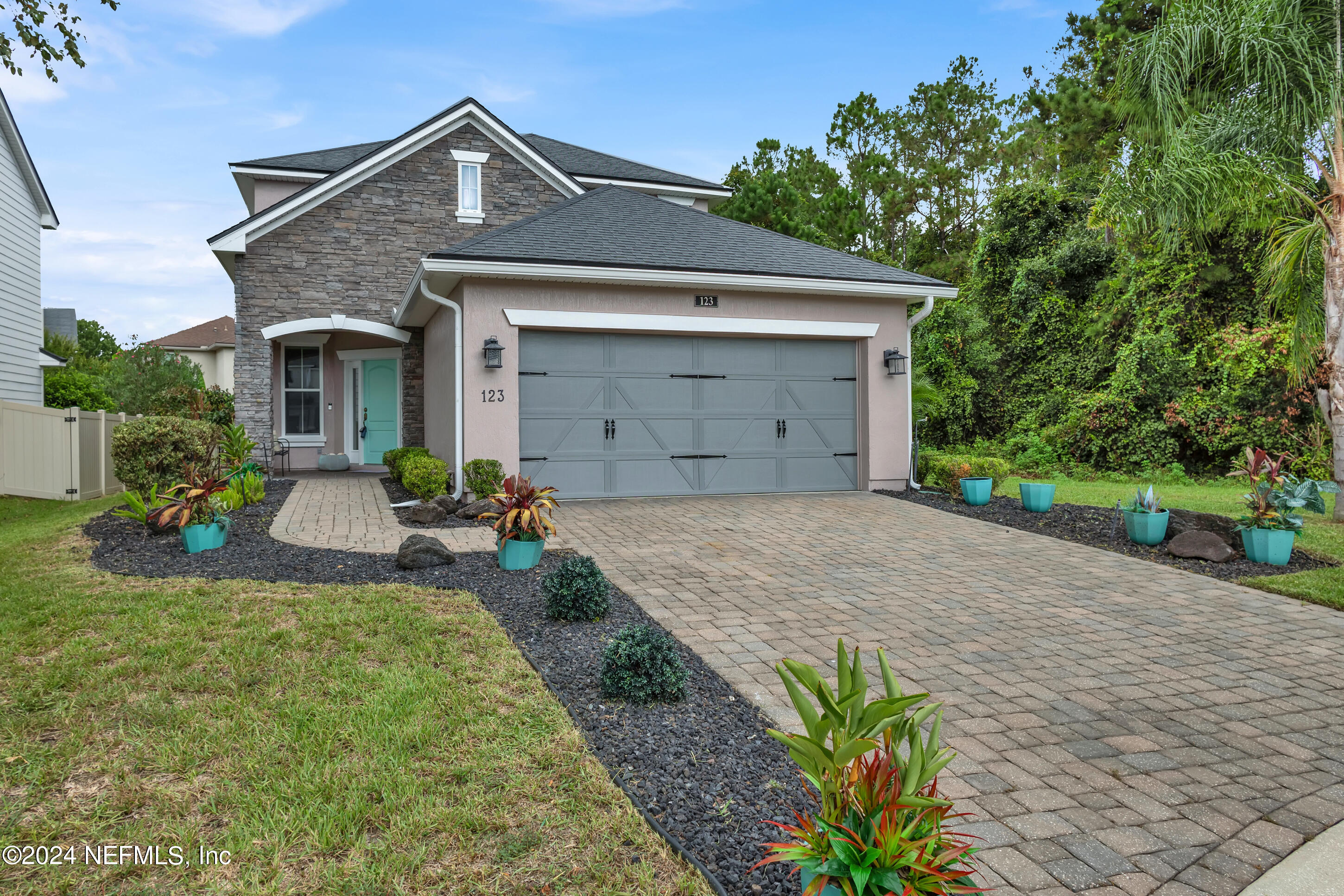 a front view of a house with a yard and potted plants